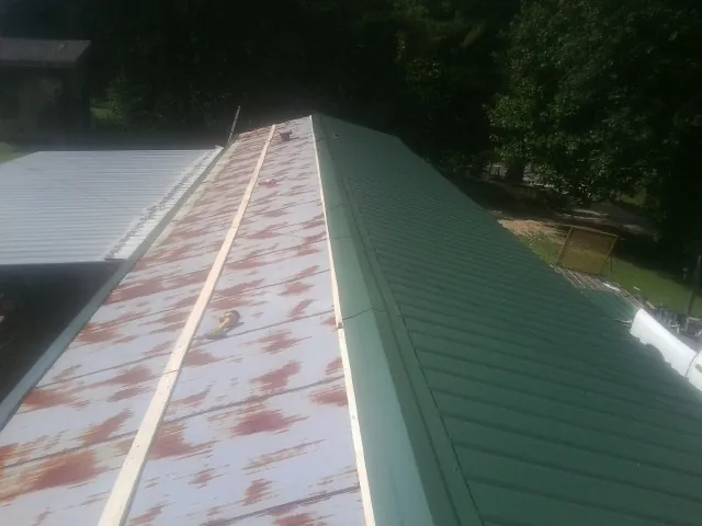 Old rusted panels beside newly installed green metal roofing — Wind Damage Roof Repair by Roofing Brothers in Fountain