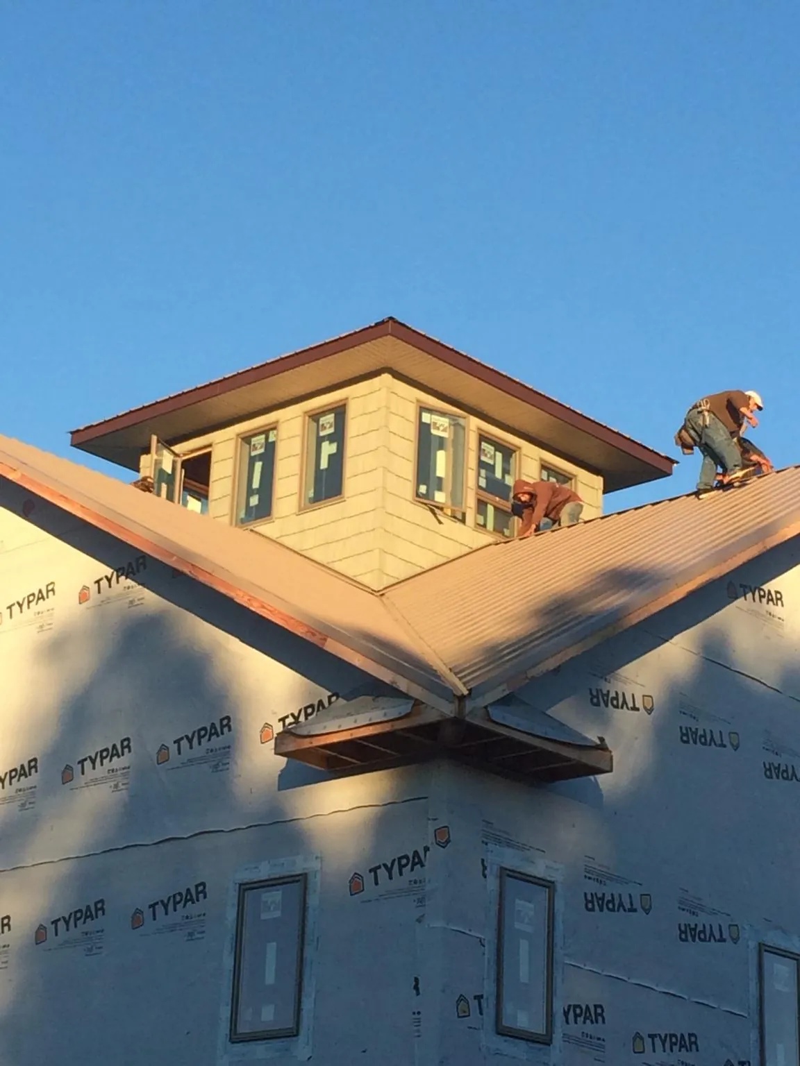Roofers working around a rooftop cupola on a new metal roof at sunset — Roof Waterproofing in Fountain by Roofing Brothers